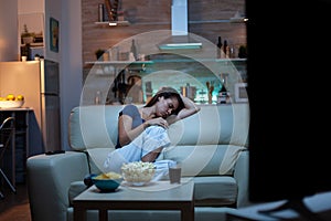 Woman sleeping on a sofa in front of TV