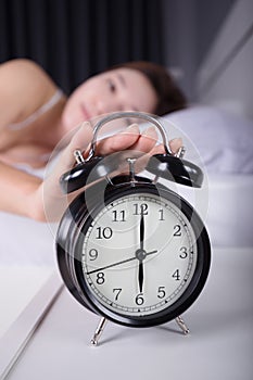 woman sleeping and wake up to turn off the alarm clock in morning