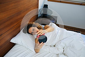 Woman sleeping and wake up to turn off the alarm clock in the morning.