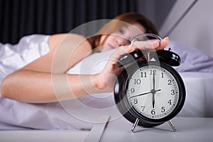 woman sleeping and wake up to turn off the alarm clock in morning