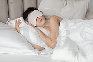 Woman sleeping wearing sleep mask in comfortable bed