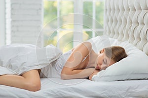 Woman is sleeping on a white bed.