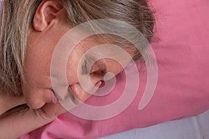 Woman sleeps on the side holding hands under the cheek. Close-up portrait of 40 years woman with calm and relax face sleeping on