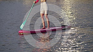 Woman with slender legs floating on paddle board