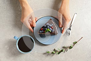 Woman with slice of chocolate sponge berry cake at table