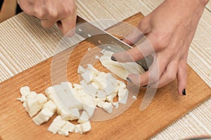 Woman slices cheese on a cutting board