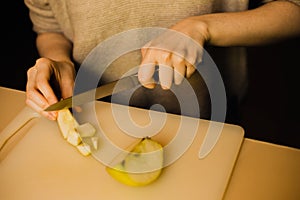 A woman slices through a crisp apple, revealing its juicy flesh. This image highlights themes of domesticity, nourishment, and