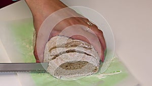 Woman slices freshly baked wholegrain bread. Baking bread at home.