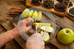 Woman slicing apples with knife for cooking pie.