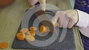 Woman slicing carrot on kitchen table