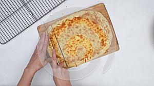 Woman slicing flat bread on wooden cutting board, close up video