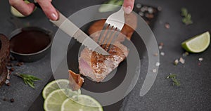 Woman slicing Fried grilled piece of Organic Tuna Steak on a black stone serving board