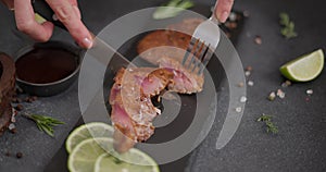 Woman slicing Fried grilled piece of Organic Tuna Steak on a black stone serving board