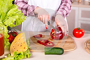 Woman slicing pepper on woden board