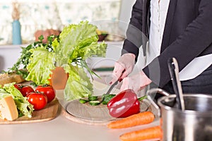 Woman slicing vegetables on wodern board