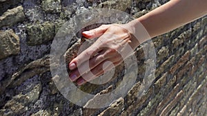 Woman slide hand against old red brick wall in slow motion. Female hand touch rough surface of stone