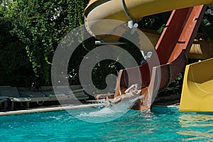Woman slides down from the slide into the pool