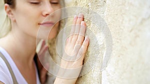 Woman sliding hand against old stone wall in slow motion. Female hand touching rough surface of rock