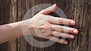 Woman sliding hand against old wooden door in slow motion. Female hand touch rough surface of wood