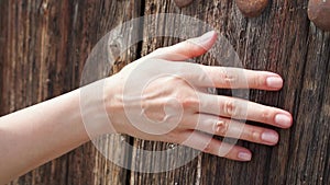 Woman sliding hand against old wooden door in slow motion. Female hand touch rough surface of wood