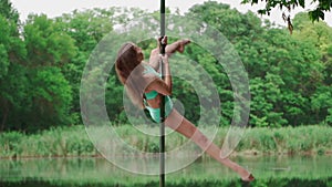 Woman with Slim Body Dancing on Background Forest and Lake. Slender Young Girl Pole Dancer Performs Acrobatic Tricks on Pylon.