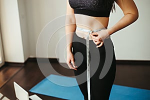 Woman with slim body measuring her waistline