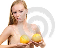 Woman small boobs holds big orange fruits