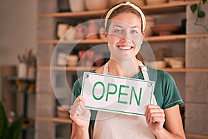 Woman, small business and open sign for creative startup, welcome or entrepreneurship at retail store. Portrait of happy