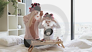 Woman with small child looking in mirror and applying moisturizing face masks.