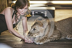 Woman with a small lion, treats, and watered it with water with