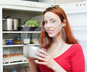 Woman with small pan near opened refrigerator