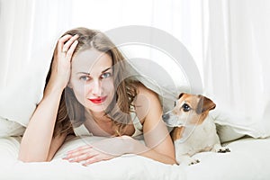 Woman with small pet dog in bed