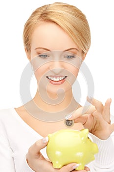 Woman with small piggy bank and coin