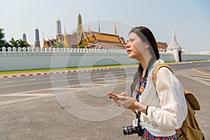 Woman on smart phone walking on grand palace