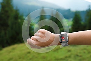 Woman with smart watch checking heart rate in health monitor app outdoors