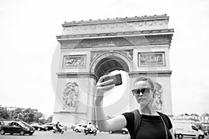 Woman with smartphone at arch monument in paris, france. Woman make selfie with phone at arc de triomphe. Vacation and