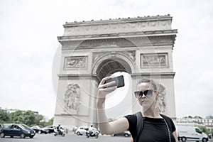 Woman with smartphone at arch monument in paris, france. Woman make selfie with phone at arc de triomphe. Vacation and