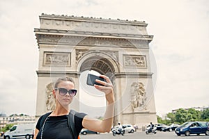 Woman with smartphone at arch monument in paris, france. Woman make selfie with phone at arc de triomphe. Vacation and