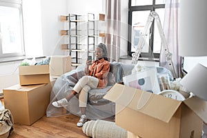 woman with smartphone and boxes moving to new home