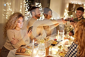 Woman with smartphone at dinner party with friends