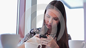 Woman with smartphone drinking cafe latte in cafe