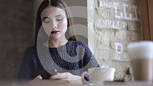 Woman with smartphone drinking coffee in cafe