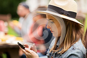 Woman with smartphone and friends at summer party