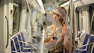 woman with a smartphone and headphones enters a subway car