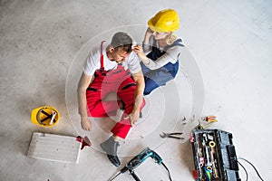 A woman with smartphone helping man worker after an accident at the construction site.