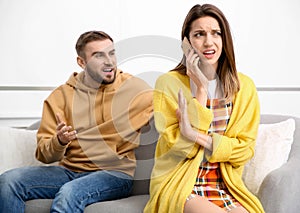 Woman with smartphone ignoring boyfriend at home. Relationship problems