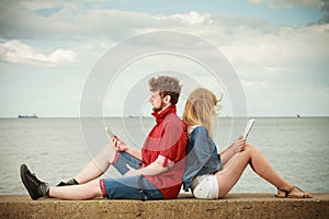 Woman with smartphone man with tablet couple outdoor