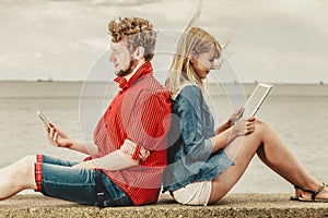 Woman with smartphone man with tablet couple outdoor