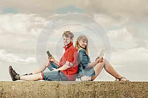 Woman with smartphone man with tablet couple outdoor