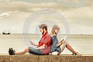 Woman with smartphone man with tablet couple outdoor